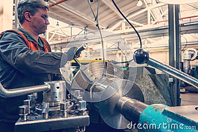 Turner worker manages the metalworking process of mechanical cutting on a lathe Stock Photo