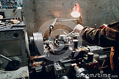 Turner worker working on old lathe machine at factory. Stock Photo