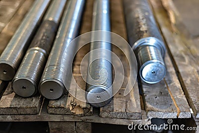 After turning and milling, the threaded studs lie on a wooden rack in the warehouse Stock Photo