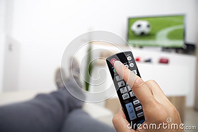 Turning off the TV. Remote control in hand. Football Stock Photo