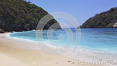 Turquoise Bay of the sea between two hills. The sea water makes the sandy shore wet. Stock Photo