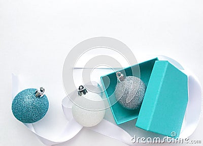 Turquoise jewelry box with a silver Christmas ball inside, on the left - Christmas glittery balls of white and blue, white ribbon Stock Photo