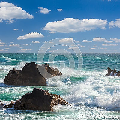 Turquoise ocean waves, rocks coastline and blue sky Stock Photo