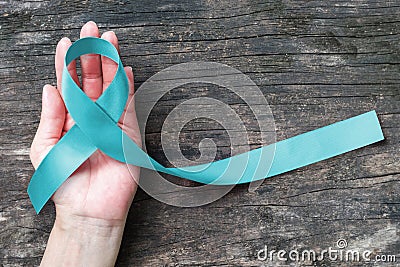 Turquoise Robin egg blue ribbon on human hand old aged background raising awareness on Bone tumor, Addiction recovery Stock Photo