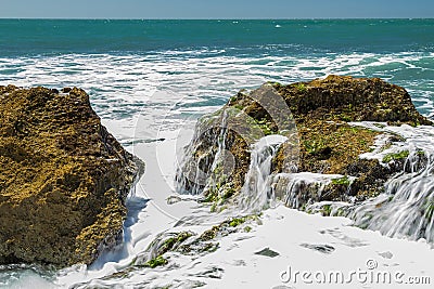 Turquoise rolling wave slamming on the rocks . Stock Photo