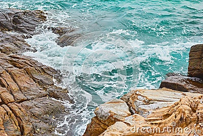 Turquoise rolling wave slamming on the rocks of the coastline Stock Photo