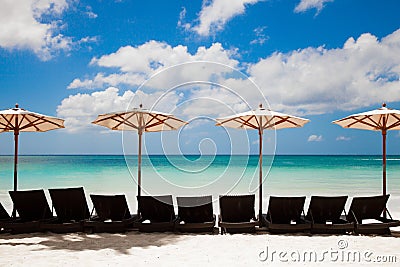 Turquoise sea, deckchairs, white sand and beach umbrellas. Stock Photo