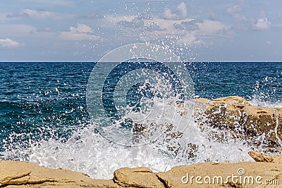 Turquoise wave breaks on rocks Stock Photo