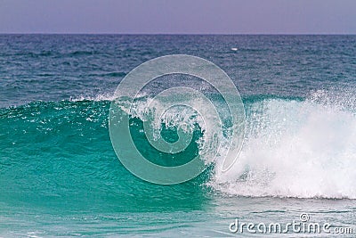 Turquoise wave breaks up to the shore Stock Photo