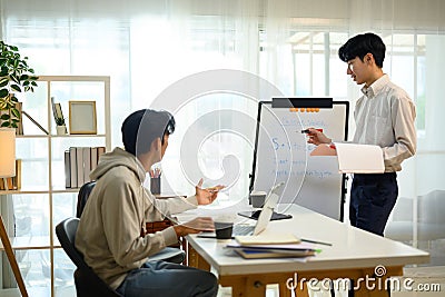 Tutor explaining grammar rules on a whiteboard while student listens and asks questions Stock Photo