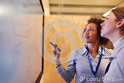 Tutor With Female Trainee Electrician Looking At Wiring Diagram On Screen Stock Photo