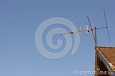 TV analog antenna on the roof of the house, against the blue sky Stock Photo