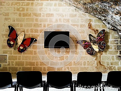 TV hanging on a brick wall surrounded by butterflies in an ancient cave Editorial Stock Photo