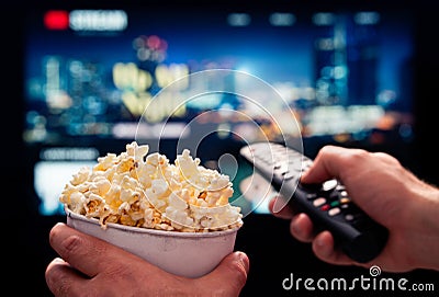 Tv movie night with family. Stream VOD platform. Popcorn and remote control. Video entertainment and snack. Play online. Stock Photo