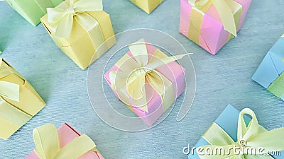 Twelve square gift boxes in rainbow light gradient colors are neatly arranged on a blue-green watercolor textured background. Stock Photo