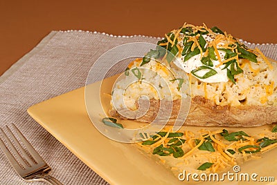 A twice baked potato with scallions, cheese and sour cream Stock Photo