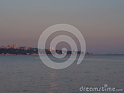 Twilight seascape with a city on the coast in the distance Stock Photo