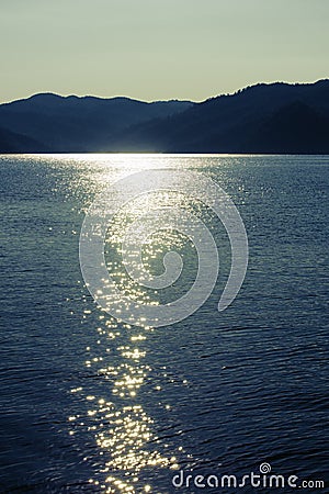 Twilight seascape. Mountains and sun glint in the water Stock Photo