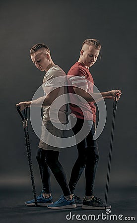 Twin brothers stand back to back and pump up biceps. on black background Stock Photo