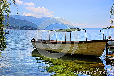 A twin-engine wooden boat with a roof on a cristal clear lake. Editorial Stock Photo