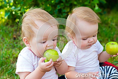 Twin girls eat apples in nature in fresh Stock Photo