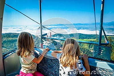 Twin girls riding cabin cable car and enjoying the view. Stock Photo