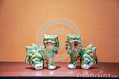 Twin green seramic lion stand in the middle of frame with tungsten light Stock Photo