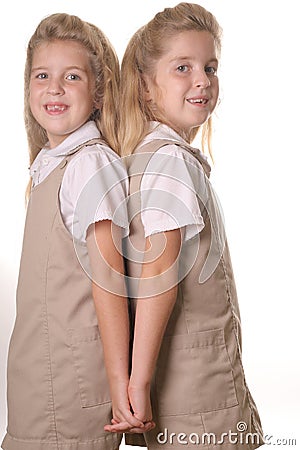 Twin school girls vertical holding hands back Stock Photo