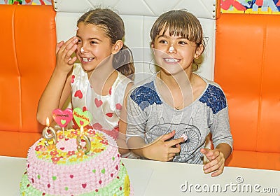 Twin sisters at birthday celebration with cake Stock Photo