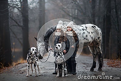 Twins girls portrait with Appaloosa horse and Dalmatian dogs Stock Photo