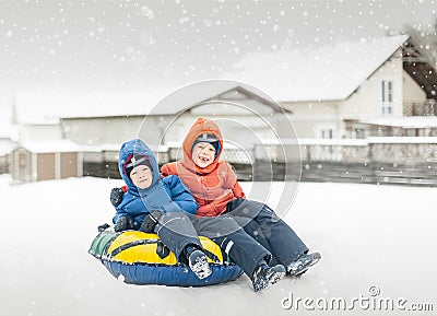 Twins play snowfall time with the inflatable sledge, snow tube Stock Photo
