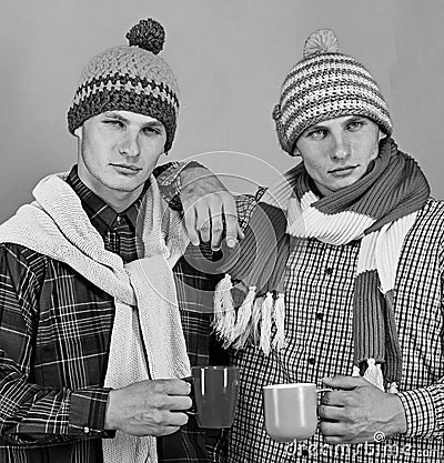 Twins with serious faces hold cups. Autumn season and friendship Stock Photo