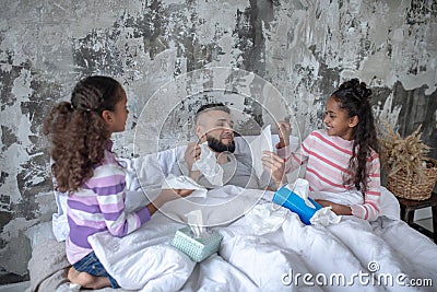 Twins taking care of daddy staying in bed after catching cold Stock Photo