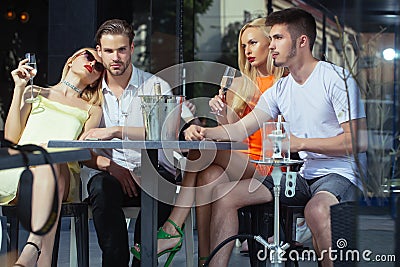 Twins women and men relax in shisha cafe outdoor Stock Photo