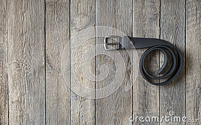 Twisted black male leather belt on a wooden background Stock Photo