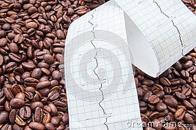 Twisted type of electrocardiogram with printed ECG line lies on fried coffee beans. Impact coffee and caffeine on heart and heart Stock Photo