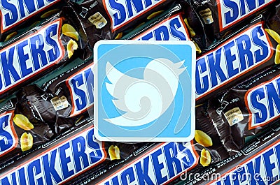 Twitter paper logo on many Snickers chocolate covered wafer bars in brown wrapping. Advertising chocolate product in Twitter Editorial Stock Photo