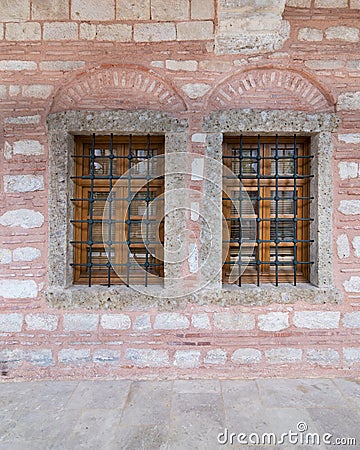 Two adjacent wooden arched windows in a red and white stone bricks wall, near Eyup Sultan Mosqoe, Istanbul, Turkey Stock Photo