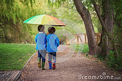 Two adorable little boys, walking in a park on a rainy day, play Stock Photo