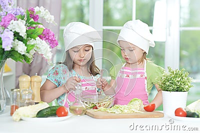 Two adorable little girls in aprons preparing delicious salad Stock Photo