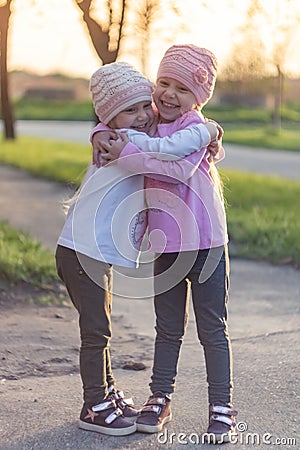 Two adorable twin little sisters laughing and hugging each other Stock Photo