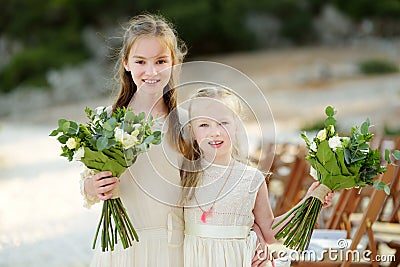 Two adorable young bridesmaids holding beautiful flower bouquets after wedding cemerony outdoors Stock Photo