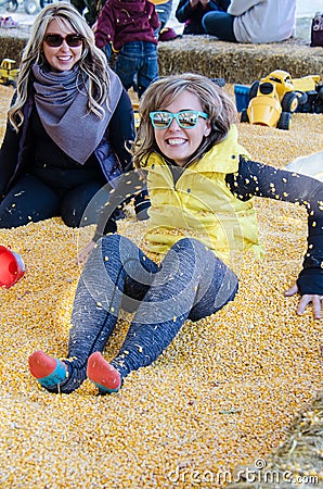 Two adult females bury each other in a corn pit at a corn maze Stock Photo