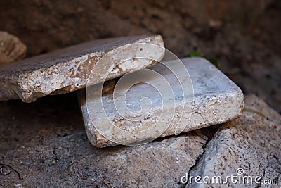 Two aged gray concrete tiles stacked into pile on brick wall Stock Photo