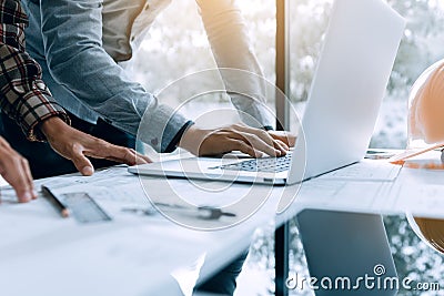 Two architect people working on laptop and checking blueprints i Stock Photo