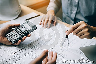 Two architect working at construction site and compass drawing pointing on blueprint with calculator calculate Stock Photo