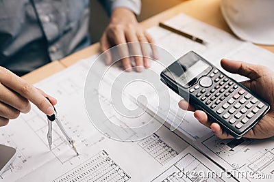 Two architect working at construction site and compass drawing pointing on blueprint with calculator calculate Stock Photo