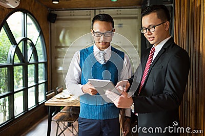 Two Asian businessman looking and point finger to detail in notebook, they are meeting and talking about business plan Stock Photo