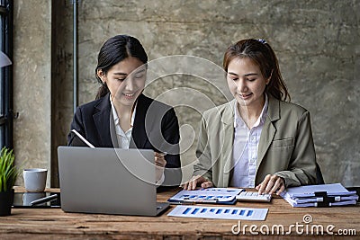 Two Asian female accountants have team meeting to summarize financial information in business office, Stock Photo