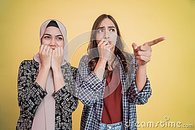 two asian girls scared expression with finger pointing gesture Stock Photo